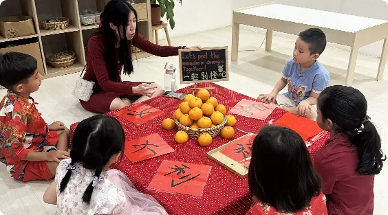 Children peeling mandarin orange with their teacher at Apple Tree Playhouse bilingual childcare in Yishun