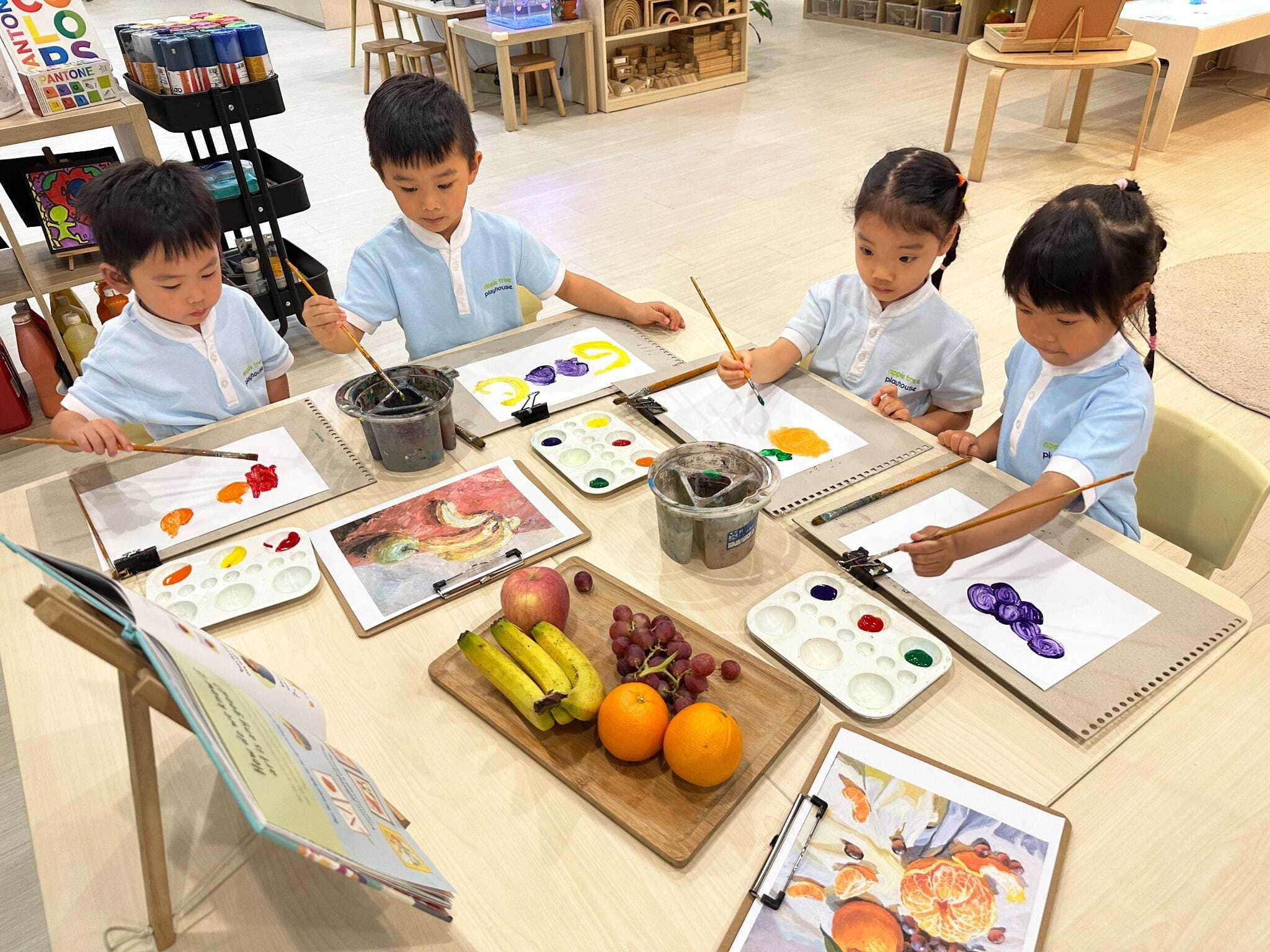 Children participating in a fruit-themed painting activity in a preschool classroom